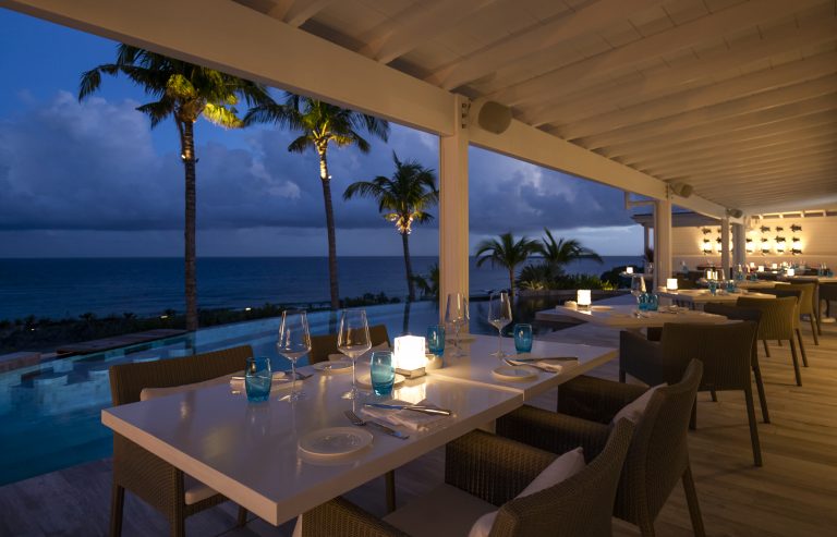 Poolside dining tables at restaurant Jarad at Le Toiny in St Barts with views of the Caribbean sea