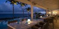 Poolside dining tables at restaurant Jarad at Le Toiny in St Barts with views of the Caribbean sea